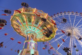 Illuminated carousel and Ferris wheel at night in a lively amusement park, funfair, wave flight,