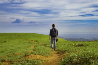 Backpacker walking on a beautiful hill. View of backpacker man walking on the beautiful hill