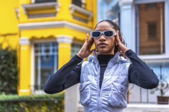 Modern african american young woman placing sunglasses standing in a colorful street