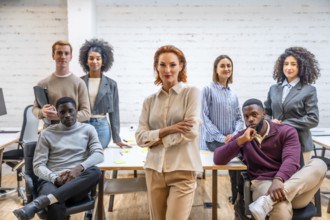Portrait of a female manager standing next to coworking colleagues sitting around a table