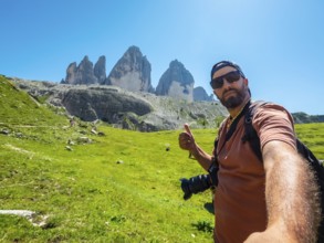 Photographer taking a selfie while hiking showing thumbs up sign with tre cime di lavaredo