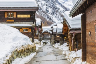 Street with historic old snow-covered wooden houses, mountain village of Zinal, Val d'Anniviers,