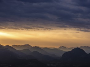 Alpine panorama under an overcast sky, illuminated by the sun through a gap in the clouds,