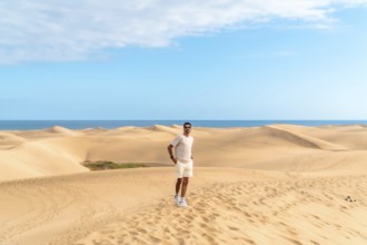 Tourist exploring the scenic landscape of maspalomas dunes with the ocean in the background