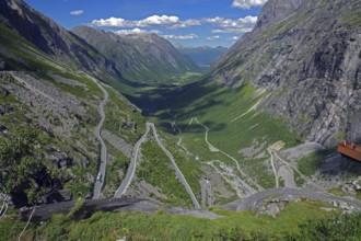 View over a winding mountain road and a narrow valley, rough rocks, small viewing platform,