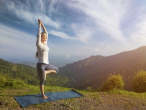Yoga practice outdoors, woman practices balance yoga asana Vrikshasana tree pose in Himalayas