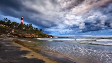 Panorama of gathering storm on beach and Kovalam (Vizhinjam) lighthouse on stormy sunset. Kerala,