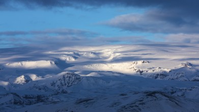 Light and shadow over the snowy hills and mountains of Myrdalsjökull, Sudurland, Iceland, Europe