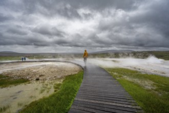 Tourist on a wooden path, steaming hot springs, Hveravellir geothermal area, Icelandic highlands,