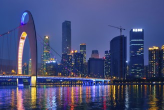 Guangzhou cityscape skyline over the Pearl River with Liede Bridge illuminated in the evening.