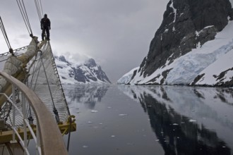 Sailing ship with man on bowsprit looking into the Lemaire Channel, Kodak Gap, Antarctica