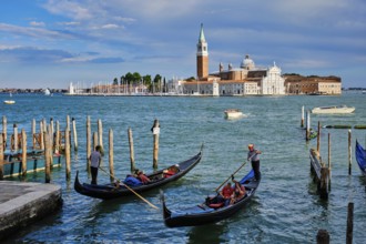 VENICE, ITALY, JUNE 27, 2018: Gondolier with tourists in gondola in lagoon of Venice by Saint Mark