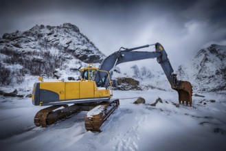 Old excavator with excavator bucket in winter. Road construction in snow. Lofoten islands, Norway.