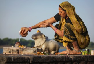 MAHESHWAR, INDIA, APRIL 26: Indian woman performs morning pooja on sacred river Narmada ghats on