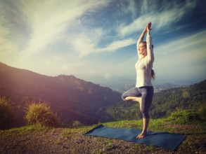 Yoga practice outdoors, woman practices balance yoga asana Vrikshasana tree pose in Himalayas
