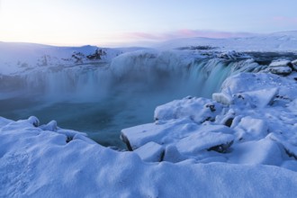 Icefall at the edge of the Godafoss waterfall at dawn, snow-covered landscape, Northern Iceland