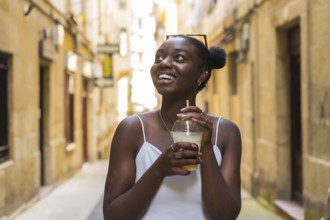 African woman looking up with amazed expression while drinking a take away milkshake visiting a