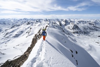 Mountaineer on a narrow mountain ridge in winter, summit of Piz Grialetsch, view of mountain