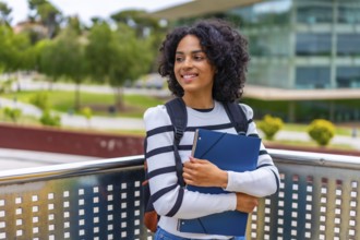 Latin female student smiling standing outside the campus of the university holding folder and