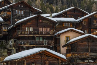 Old wooden houses with snow-covered roofs in the historic village centre, Grimentz, Val