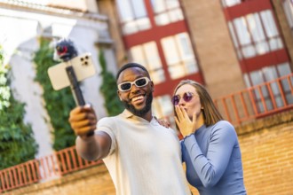 Multi-ethnic couple using mobile phone handheld gimbal for vlogging outdoors