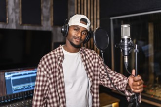 Young artist wearing headphones recording vocals for new song or album in professional recording