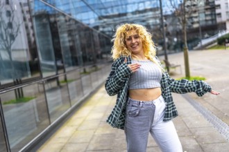 Smiling young woman with curly blonde hair dancing a modern urban dance style in the city