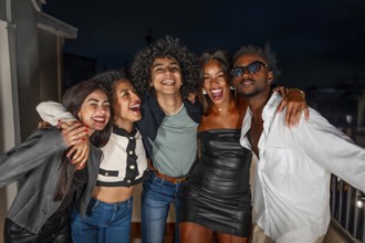 Portrait of multi-ethnic group of males and females friends embracing from the shoulder partying at