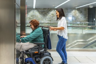 Side view of a chinese female caregiver pushing wheelchair of a caucasiana adult disabled woman