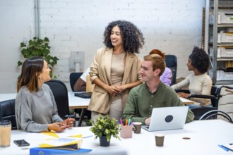 Three diverse females and male coworkers talking distracted in a modern coworking room