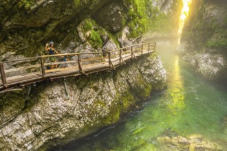 Tourists enjoying a scenic walk along the wooden pathway above the emerald radovna river,