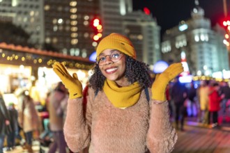 Young woman wearing yellow winter clothes enjoying christmas market in plaza de espana, madrid, at