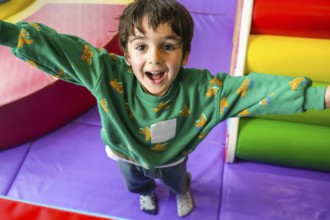 Preschooler enjoying playtime in colorful indoor playground, expressing pure happiness and