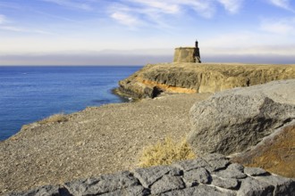 Coastal landscape with historic defence defence tower on a cliff and calm sea under a blue sky,