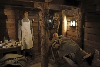 Diorama of WWI British almoner and doctor treating wounded soldier in dugout of WW1 trench at
