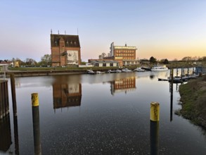 Harbour view at sunset with reflecting buildings on calm water, old warehouses, hotel, Elbe,