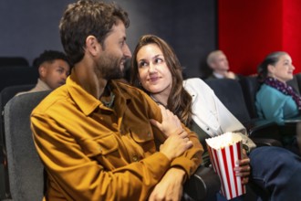 Couple enjoying a cozy movie night, sharing popcorn and affection while surrounded by a lively