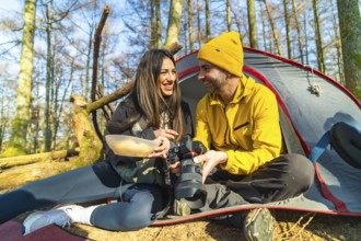 Couple of photographers camping and having a meal while reviewing photos they have taken in the