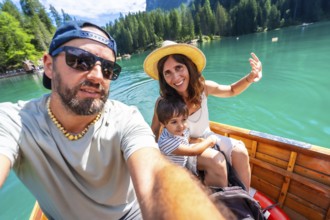 Happy family with a child taking a selfie while enjoying a boat trip on the beautiful lake braies