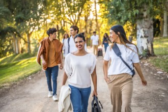 Frontal view of two caucasian smiling and relaxed women talking strolling at park with friends