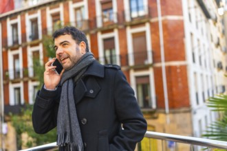Adult caucasian man in elegant warm clothes talking to the mobile standing in the city