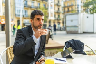 Businessman enjoying morning coffee while working with smartphone and digital tablet in an outdoor