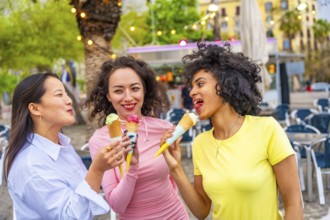 Three diverse young female friends eating ice cream enjoying summer in the city