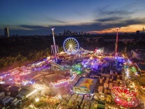 The lights of the Dippemess in Frankfurt am Main glow after sunset. Aerial view, ice rink,