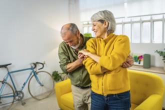 Happy mature couple dancing together and smiling at home
