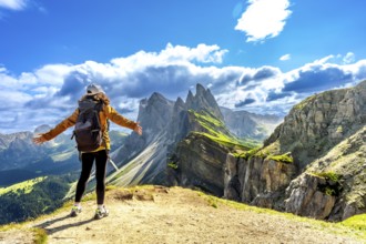 Hiker with open arms enjoying the breathtaking view of the odle mountains in seceda, dolomites,