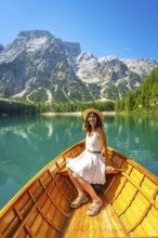 Young woman relaxing on a wooden rowboat, enjoying the breathtaking scenery of lake braies and the