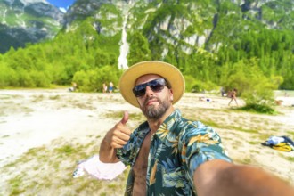 Happy tourist showing thumbs up while taking a selfie at lago di landro, also known as durrensee