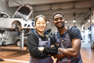 Two smiling mechanics with arms crossed, showcasing confidence and professionalism in a busy car