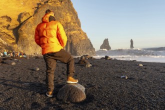 A tourist looking at the beautiful Reynisfjara Black Sand Beach in Iceland in winter
